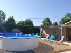 a large hot tub on a deck with chairs at Le Hangar de Papi in La Charrière