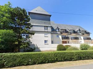 duży biały budynek z dachem gambrel w obiekcie Appartement cosy avec vue imprenable sur Cabourg - accès direct plage - proche centre ville w mieście Cabourg