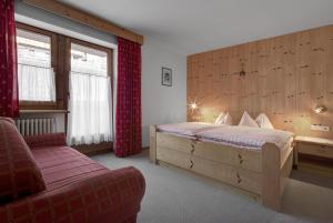 a bedroom with a large bed and a red couch at Residence Dolomieu in San Cassiano