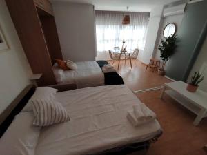 ein Schlafzimmer mit zwei Betten und einem Tisch darin in der Unterkunft Torrox Costa Loft Playa Wi-Fi Paseo Marítimo in Torrox + 19 Fotos