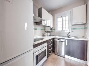 Una cocina con gabinetes blancos y electrodomésticos de acero inoxidable. en Apartment with pool near Burriana beach, Nerja, en Nerja 13 fotos más