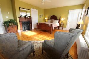 a bedroom with a bed and two chairs and a fireplace at Louisbourg Heritage House in Louisbourg