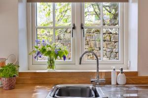 a kitchen sink with a window and a vase of flowers at Finest Retreats - Cherry Cottage Nr Grantley Hall in Grantley +20 photos
