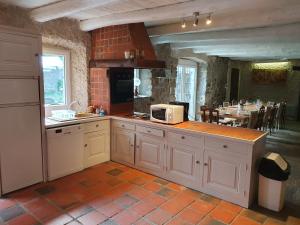 a kitchen with white cabinets and a counter with a microwave at Gîte des Ailes in Vorey