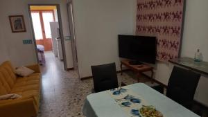a living room with a table and a television at Affittacamere Casa Chiara in SantʼAntìoco