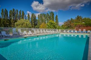 a large swimming pool with chairs and a fence at Camping Les Fontaines in Ivry-la-Bataille