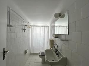biała łazienka z umywalką i lustrem w obiekcie Tinion Urban Hotel w mieście Tinos
