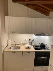 una cucina con mobili bianchi, un lavello e una stufa di Appartamento mansardato centrale Limone Piemonte a Limone Piemonte