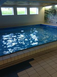 a large swimming pool in a building with windows at Chiemgau Apartments II (Schuhbaum) in Inzell