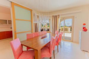 una sala da pranzo con tavolo in legno e sedie rosa di Villa Treya - Star property stunning views a Son Bou