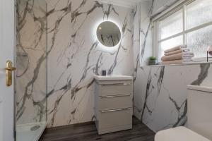 a bathroom with a marble wall with a mirror at 3 bedroom Windsor Garden apartment by Gleneagles in Blackford +21 photos