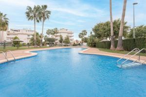 a swimming pool in a resort with palm trees at Apartamento En Canet in Canet de Berenguer