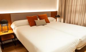 a bedroom with a large white bed with orange pillows at Apartamentos 2H LIVING in León +44 photos