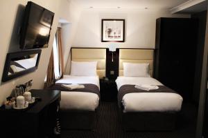 a hotel room with two beds and a television at Hotel Edward Paddington in London