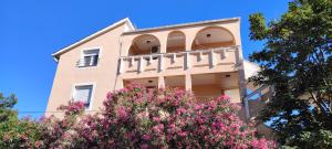 a building with pink flowers in front of it at Apartments Eufemija in Novalja