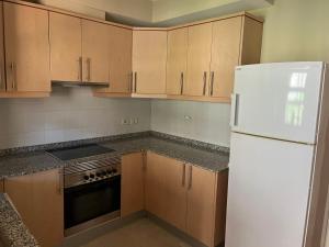 a kitchen with wooden cabinets and a white refrigerator at Apartamento-Casa buena vista in Mogán +8 photos