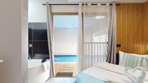 a bedroom with a window and a tub and a bed at אחוזת ריצ'מונד של רשת לב הגולן - 3 סוויטות מהממות בחד נס ליד הכנרת עם בריכה משותפת מחוממת ומקורה in Had Nes