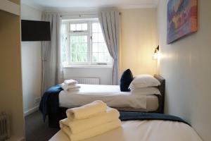 two beds in a hotel room with towels on the bed at The Barford Inn in Salisbury