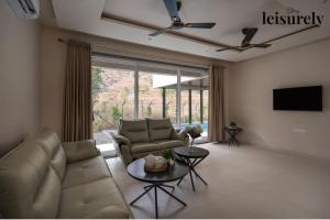 a living room with a couch and a tv at Stay Leisurely Terra 2BHK & Timber 2BHK, Igatpuri in Balayaduri