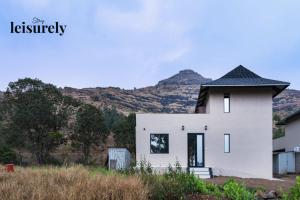 a white house with a mountain in the background at Stay Leisurely Terra 2BHK & Timber 2BHK, Igatpuri in Balayaduri