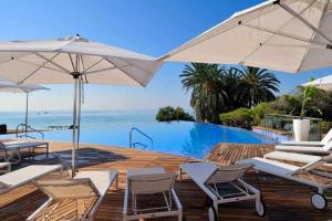 a pool with chairs and umbrellas next to the ocean at Preciosa villa con la piscina en las Colinas in Orihuela