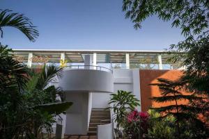 a white house with a spiral staircase in a garden at El Arbol by Da Alohas Luxury 2BHK suite Candolim in Nerul