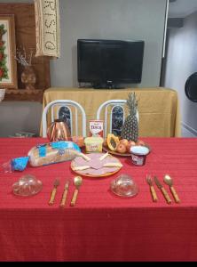 uma mesa com uma toalha de mesa vermelha com utensílios e comida em hostel praia dos ingleses em Florianópolis