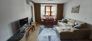 a living room with a couch and a flat screen tv at Bansko Pirin Golf & Country Club Blue Mountains View in Razlog