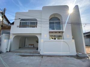 芭堤雅市中心Huang Su Villa 7 皇宿7号泳池别墅的一座白色的房子，前面有大门