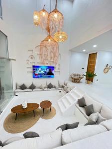 芭堤雅市中心Huang Su Villa 7 皇宿7号泳池别墅的客厅配有白色家具和吊灯。 更多18张照片