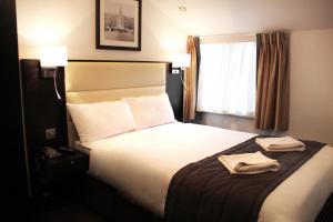 a hotel room with a bed with two towels on it at Hotel Edward Paddington in London