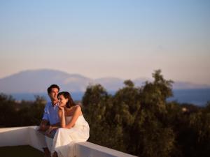 a bride and groom sitting on a wall at Hotel St.John Suites Adults Only in Tsilivi