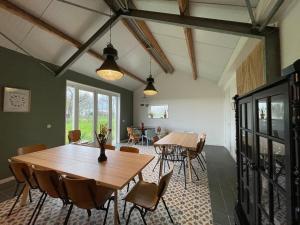 a dining room with wooden tables and chairs at Group accommodation Huize Blokland on nature farm - 14p in Hem +42 photos