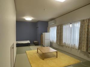 a living room with a table and a refrigerator at Guest house MICHISHIO in Kannoura