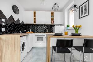 een keuken met witte kasten en een aanrecht met stoelen bij Stylish Studio Oldtown in Gdańsk