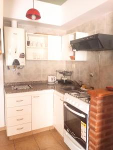 a kitchen with white cabinets and a stove top oven at Duplex Echesortu a metros de la terminal in Rosario
