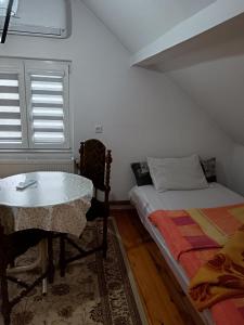 a bedroom with a bed and a table and a window at Goražde-Centar Apartment in Goražde