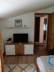 a living room with a flat screen tv on a dresser at Goražde-Centar Apartment in Goražde