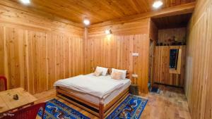 a bedroom with a bed in a wooden room at Tirthan Pine View Home stay in Gushaini