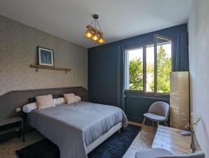 a bedroom with a bed and a chair and a window at Les Bois de Malaguet - gite d'étape et de séjour in Monlet