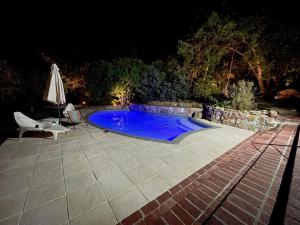 a swimming pool at night with a chair and an umbrella at Nudist Naturist FKK Port Nature Sandy Bay in Cape Town