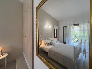 a mirror in a bedroom with a bed and a window at DoorMat #20 Beach house Mikiverna in Kalyves Poligirou