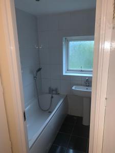 Un baño blanco con bañera y lavabo. en Lovely Milton Keynes Double Room, en Milton Keynes