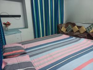 a bed with colorful sheets and pillows on it at Prayagraj Sangam Stay Home Kareli Allahabad in Prayagraj