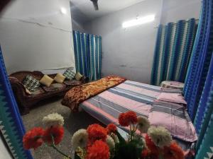 a bedroom with a bed and a couch and flowers at Prayagraj Sangam Stay Home Kareli Allahabad in Prayagraj