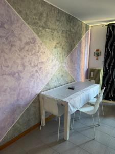 a table and chairs in a room with a wall at Michelle Luxury Living in centro a Gorizia in Gorizia +14 photos