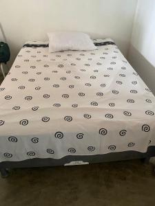 Cama en habitación con edredón blanco en Casa Cumuru, en Prado