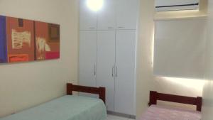 a bedroom with a bed and a cabinet and a window at Quarto aconchegante Jatiúca in Maceió