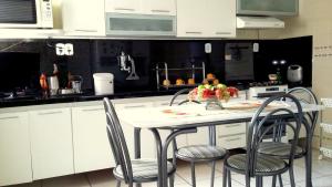 uma cozinha com armários brancos e uma mesa com cadeiras em Quarto aconchegante Jatiúca em Maceió