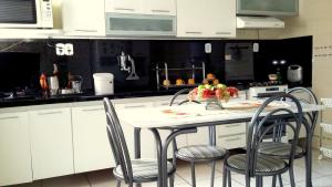 a kitchen with white cabinets and a table with chairs at Quarto aconchegante Jatiúca in Maceió